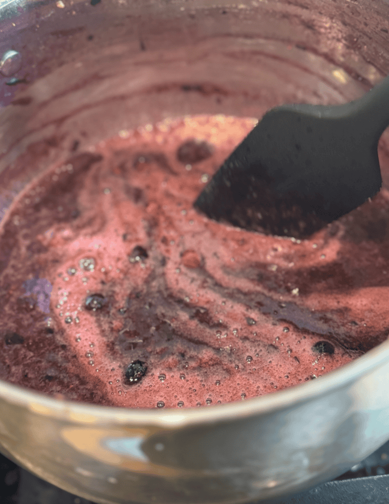 Freshly cooked strawberry jam in a pot with a spatula.