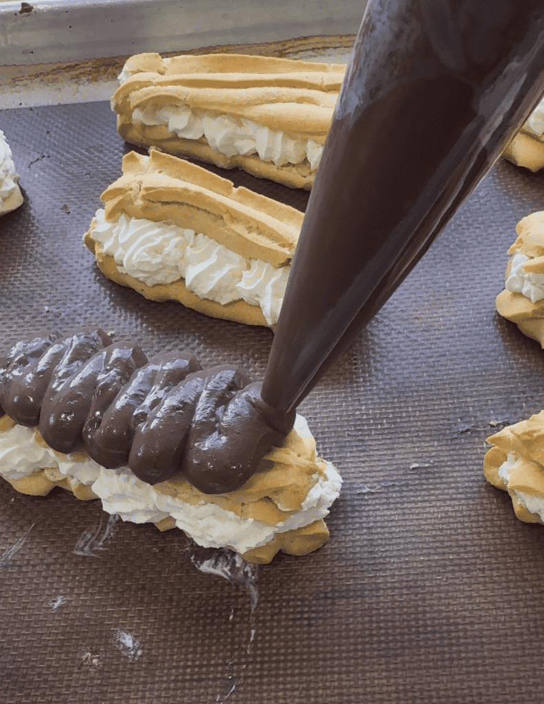 Delicious homemade eclairs filled with cream and topped with chocolate glaze. Perfect for dessert or.