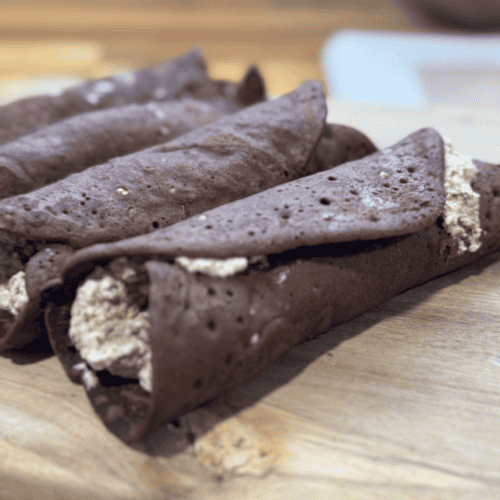 Freshly made chocolate cannoli with creamy filling on a wooden board.