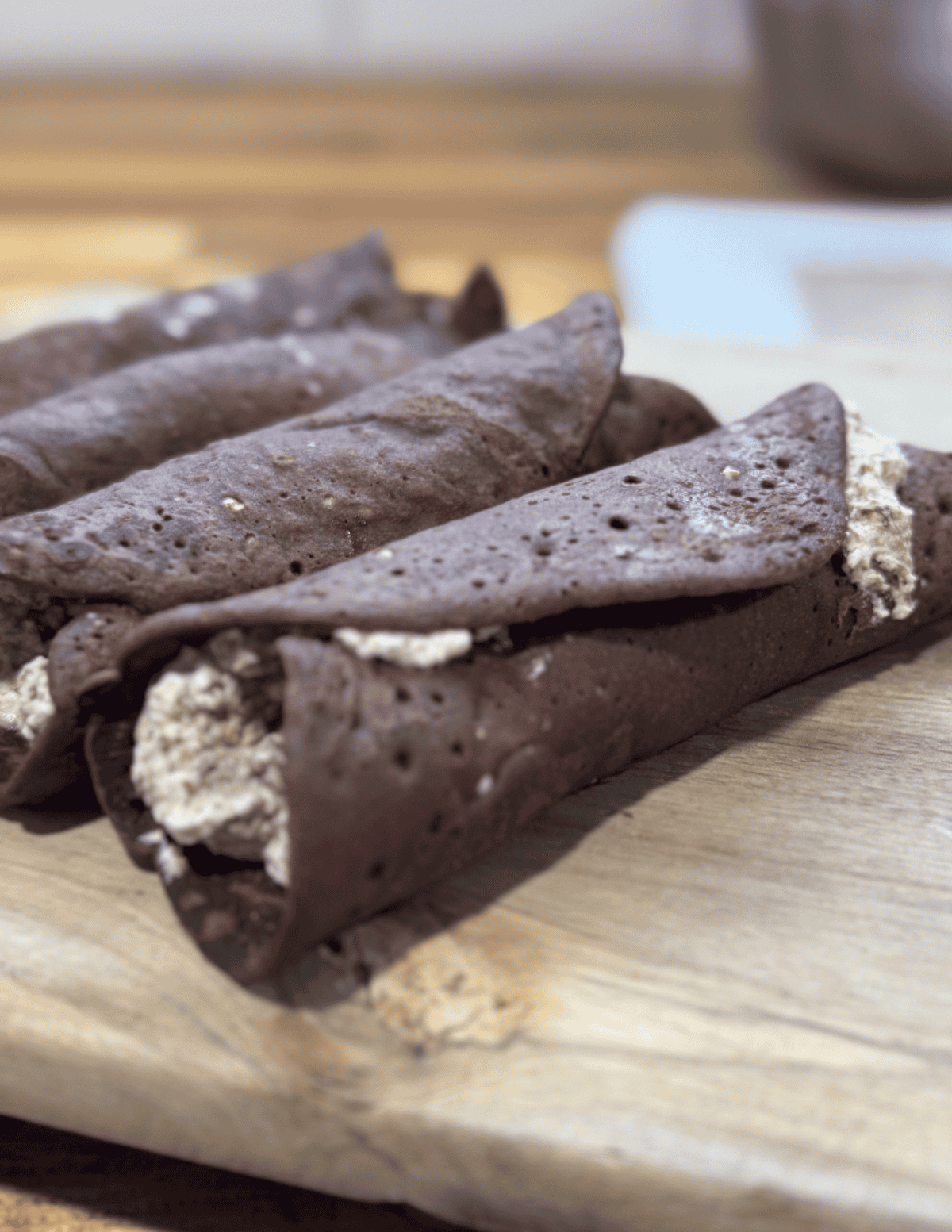 Freshly made chocolate cannoli with creamy filling on a wooden board.