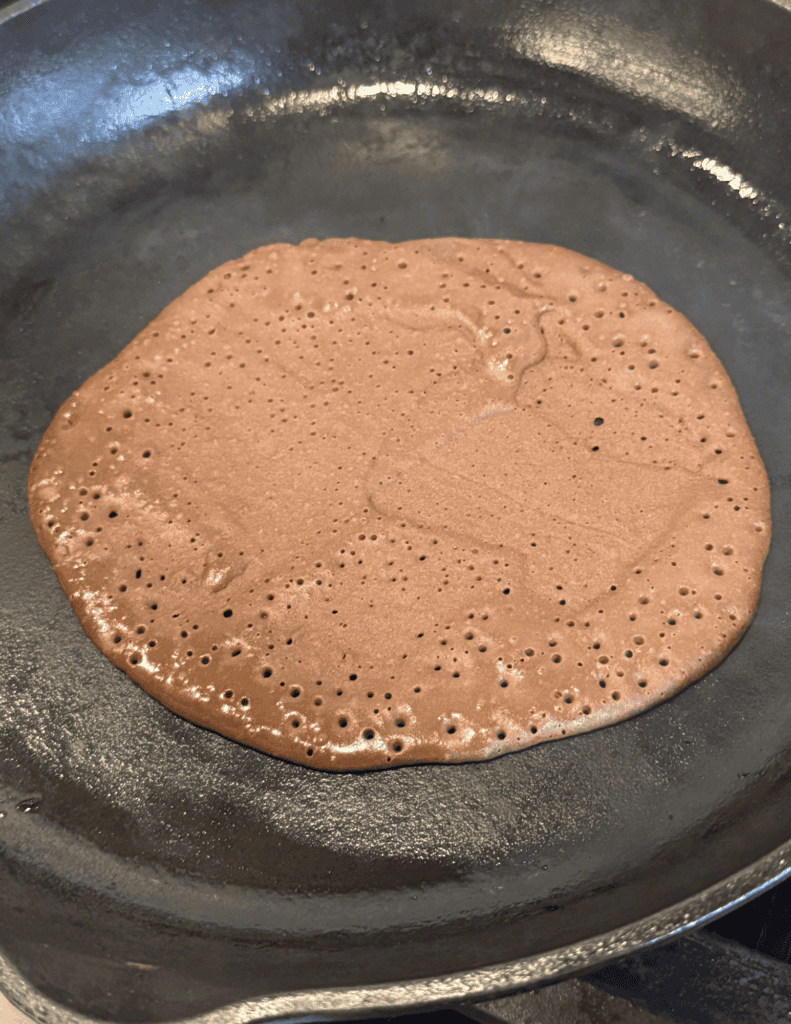 Freshly cooked chocolate pancake in a black skillet.