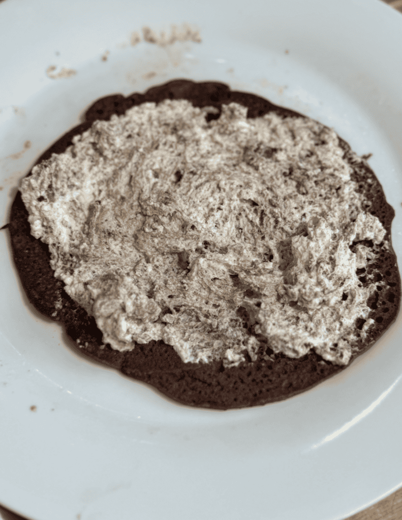 Close-up of homemade chocolate cake with frosting on a white plate.