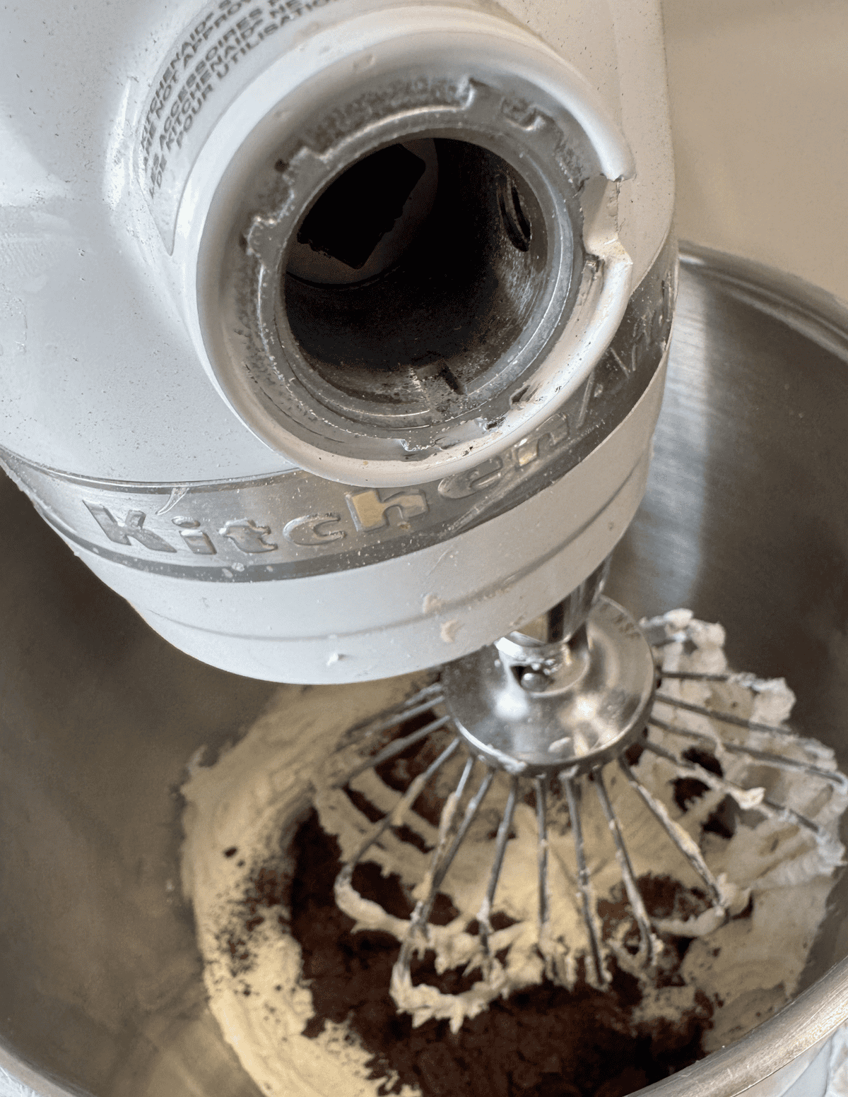 Close-up of a hand mixer blending chocolate cake batter in a mixing bowl.