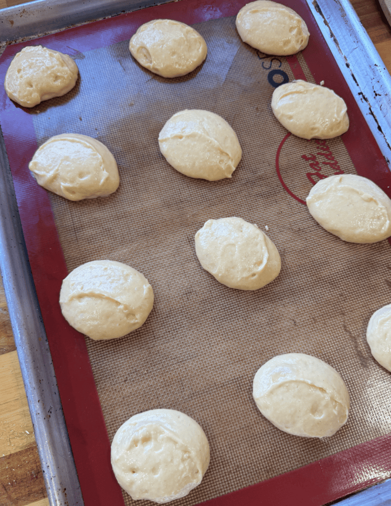 Fresh homemade bread dough balls on a baking tray ready for baking.