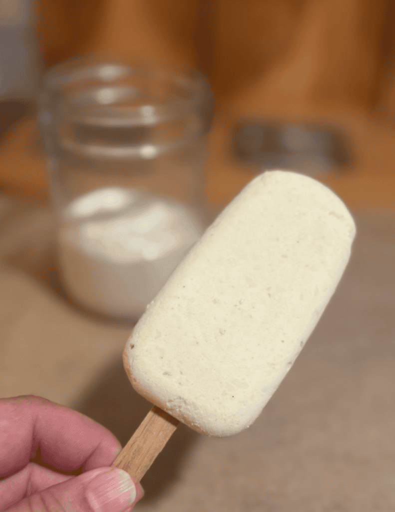 Creamy homemade ice cream bar on a wooden stick, close-up.