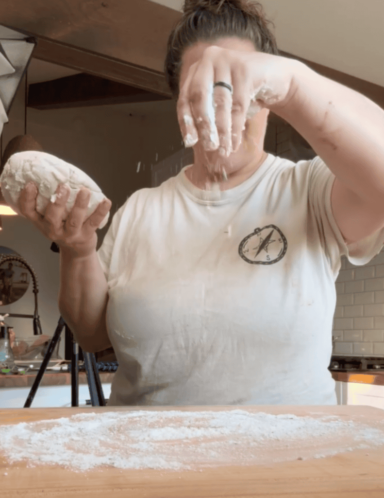 Woman kneading dough for fresh homemade bread in a cozy kitchen.