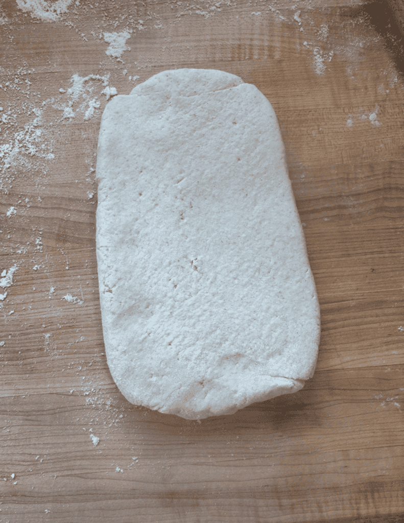 Fresh homemade pizza dough on a wooden surface, ready for baking.
