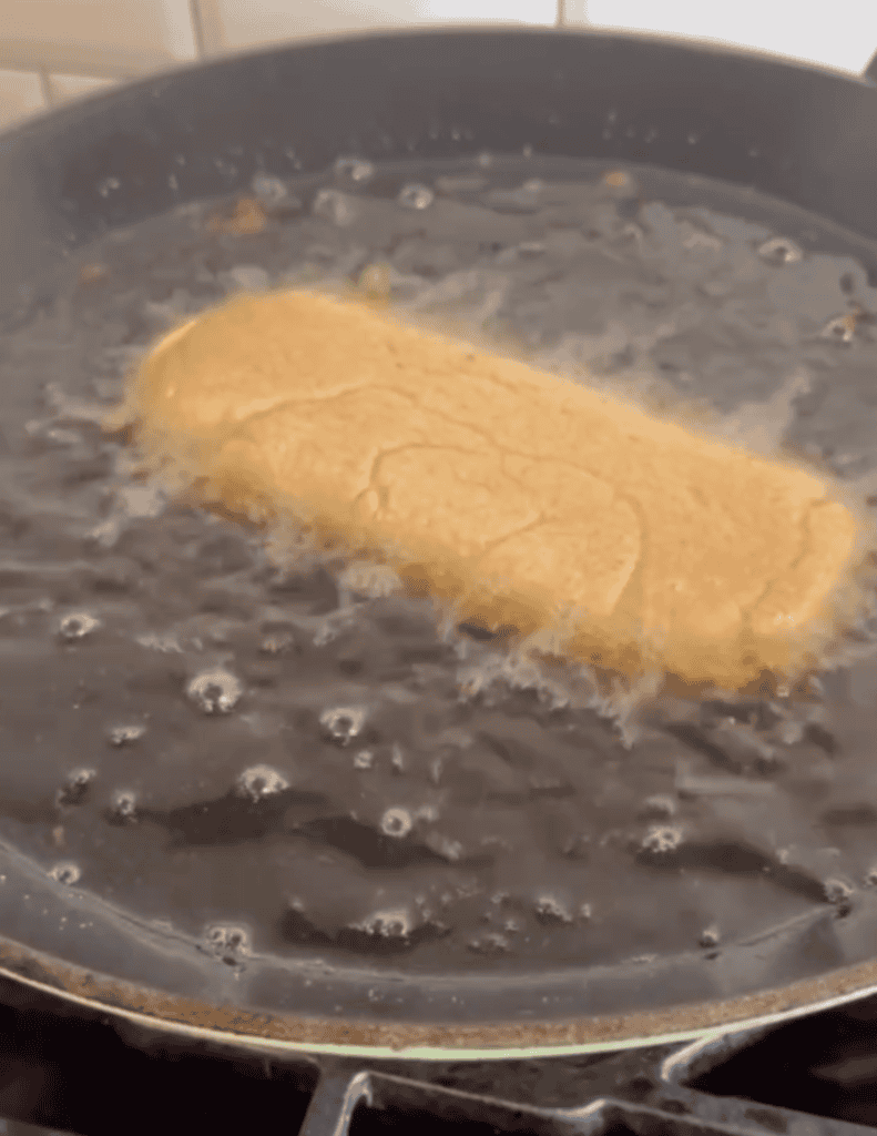 Frying a golden-brown breaded item in hot oil for a crispy texture.