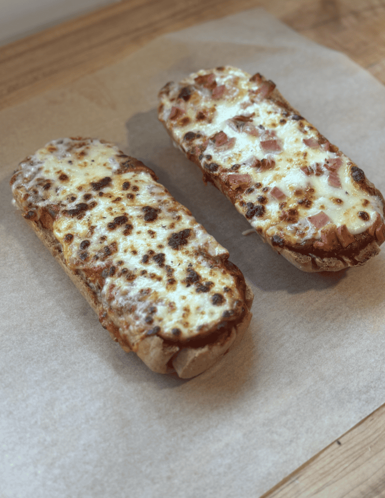 Delicious cheesy bread with ham on a wooden surface.