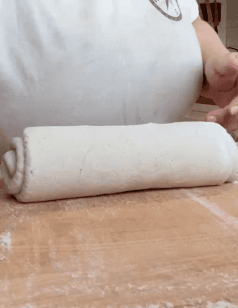 Person rolling dough on a wooden surface for baking at Farm Fresh Family.