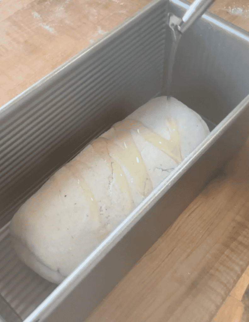 Freshly baked bread dough being rinsed in a bread pan.