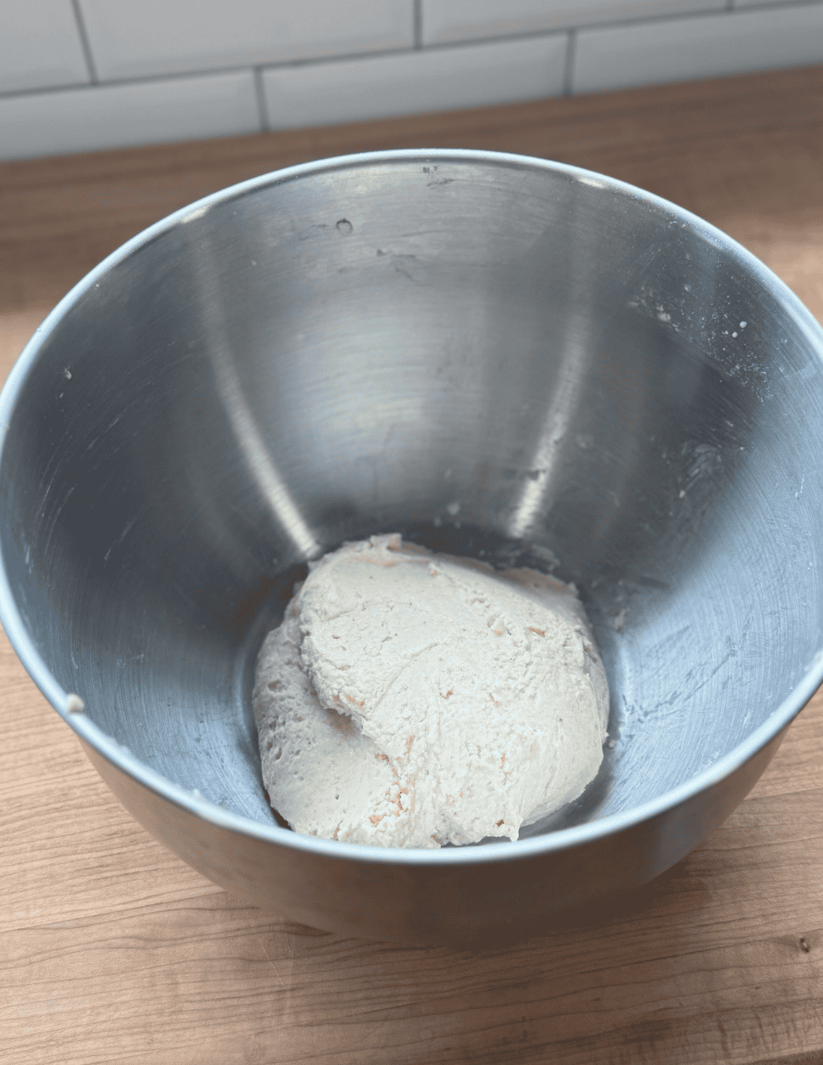 Dough ball in a stainless steel mixing bowl, ready for baking or cooking.