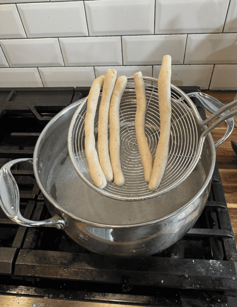 Freshly baked breadsticks cooling in a wire rack over a pot.