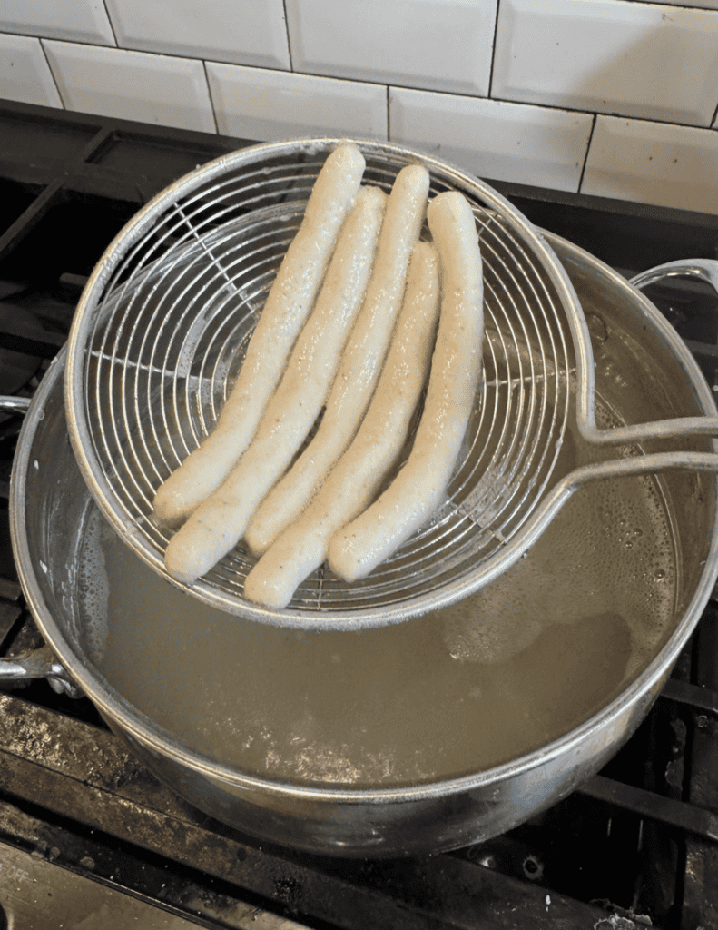Freshly cooked breadsticks draining in a wire rack over boiling water.