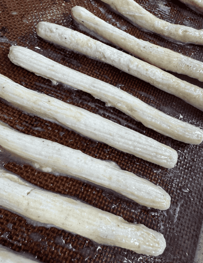 Breadsticks on a baking sheet before baking, showcasing fresh dough ready for oven.