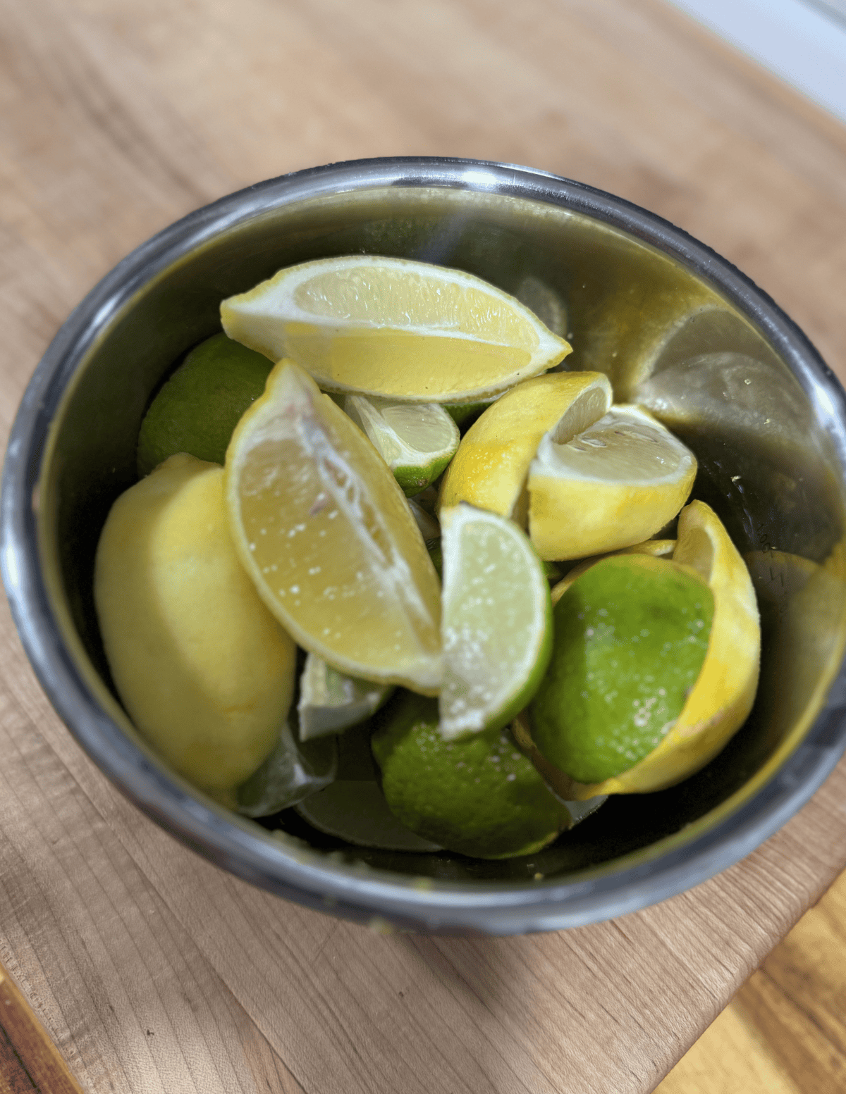 Fresh lemon and lime wedges in a metal bowl.