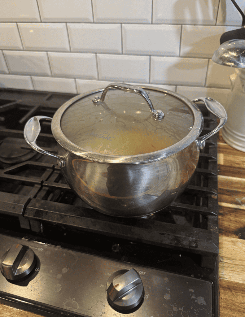 Stainless steel cooking pot with lid on a gas stove, ready for meal preparation.