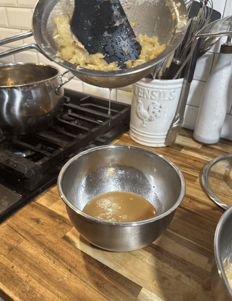 Freshly churned butter in a metal bowl on a wooden kitchen countertop.