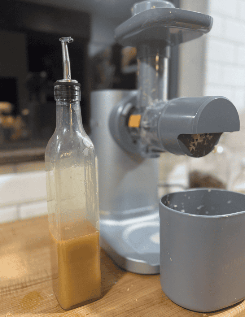 Homemade nut butter being processed with a juicer on a kitchen counter.