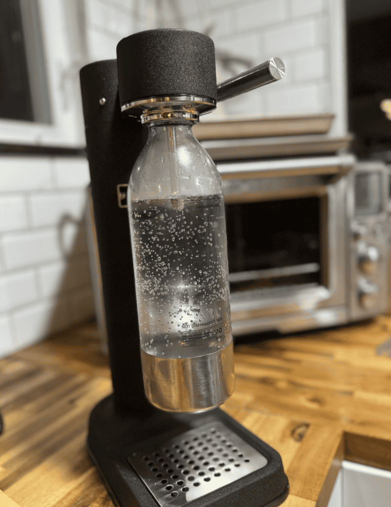 Sparkling water bottle attached to a home soda maker machine.