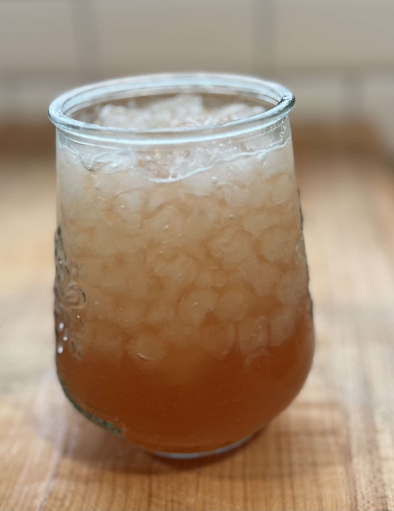 Glass of homemade lemonade with ice, served in a rounded glass on a wooden surface.