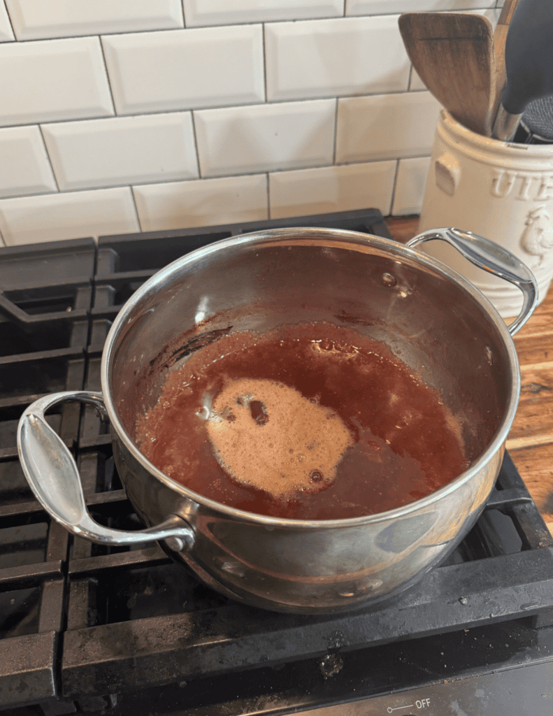 Cooking homemade jam in a stainless steel pot on the stove.