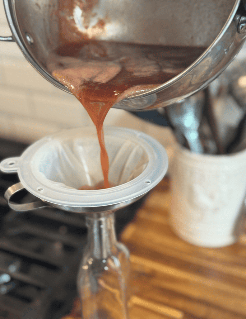 Fresh fruit juice being poured into a glass from a metal pitcher, highlighting farm-fresh produce an.