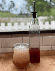 Fresh fruit juice served in a glass and bottle on a wooden table.