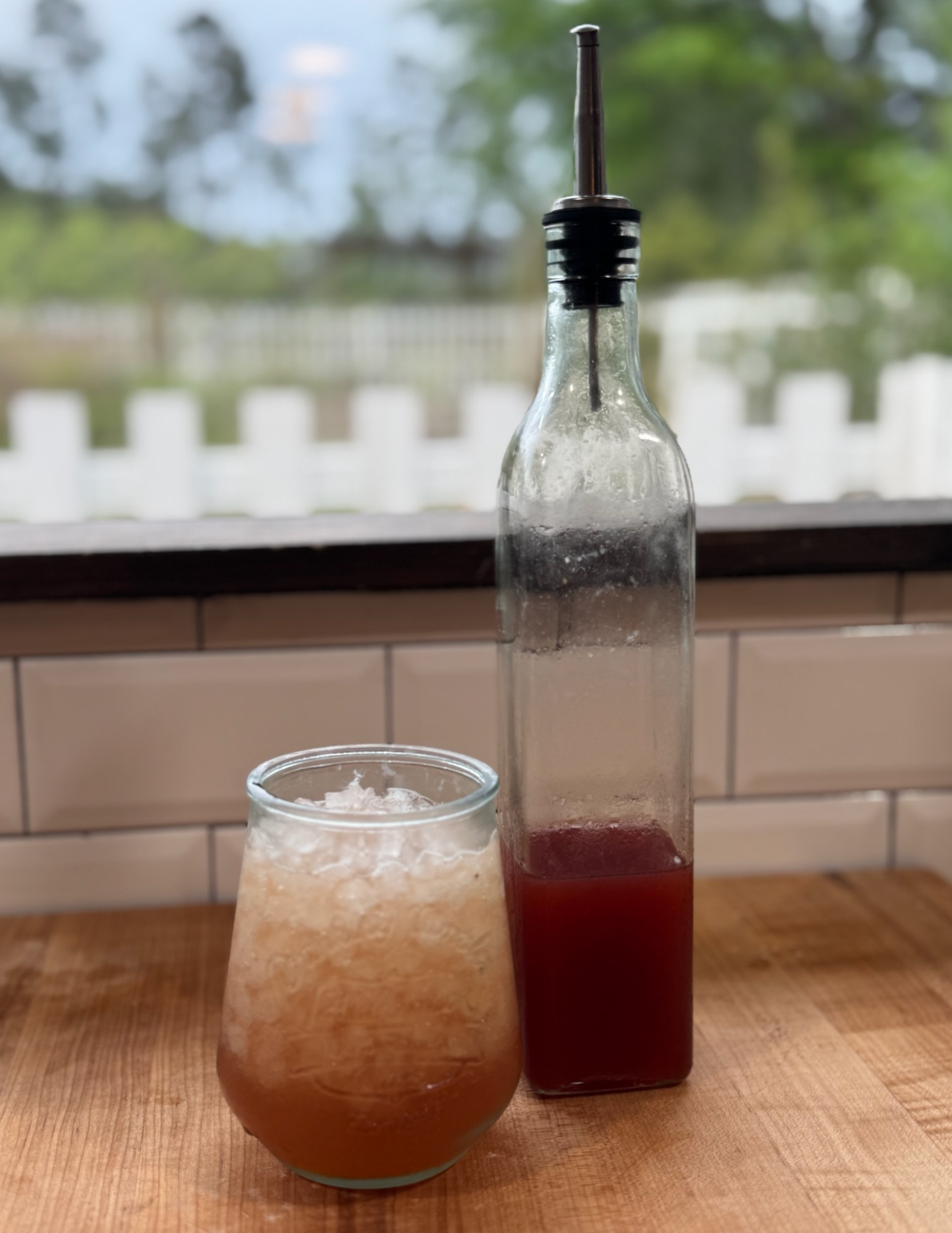 Fresh fruit juice served in a glass and bottle on a wooden table.
