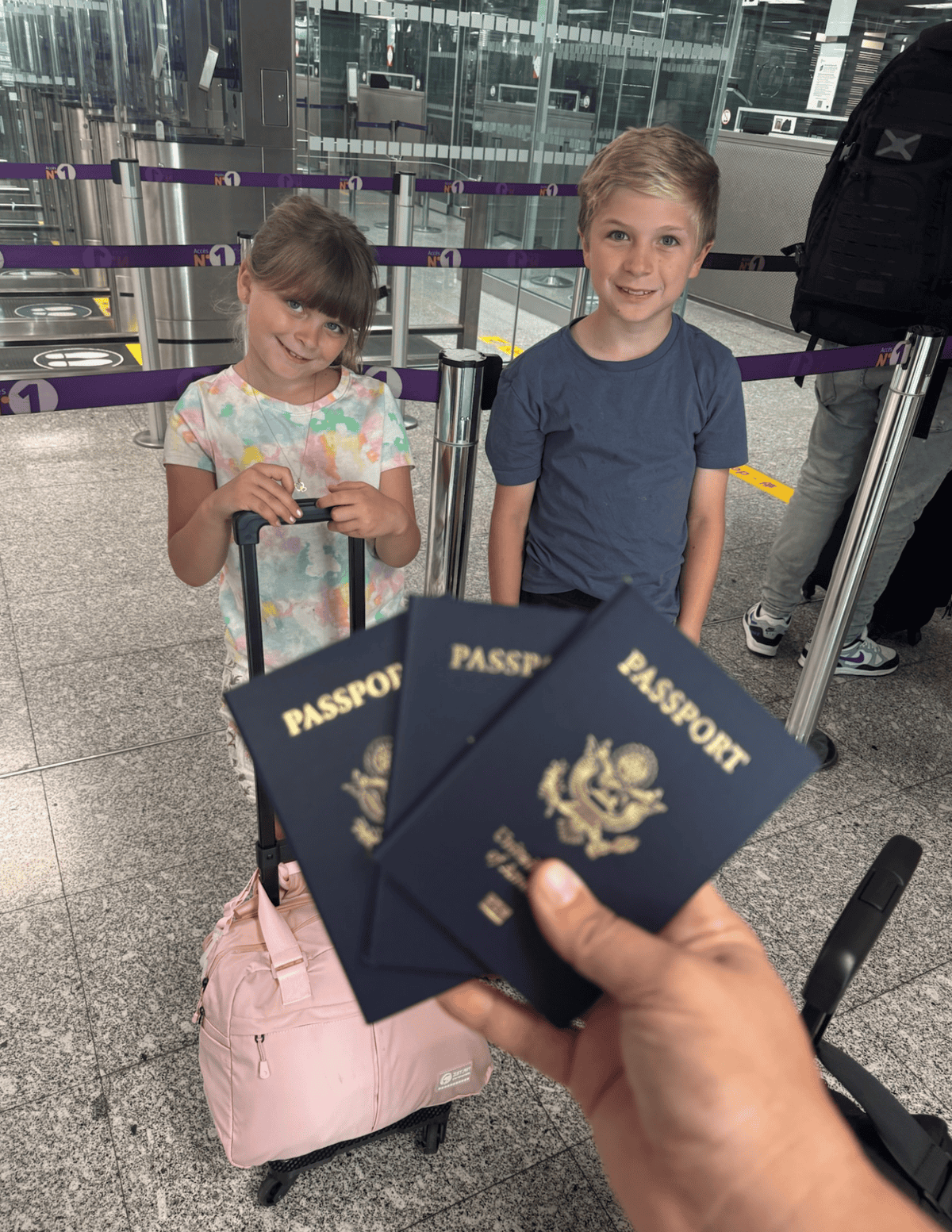 Children with passports and luggage at airport check-in.