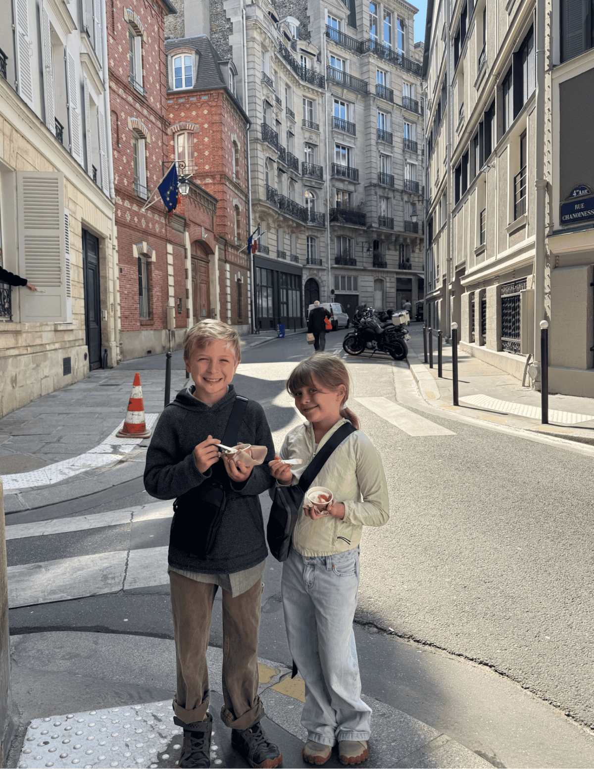 two kids eating gelato on the corner of a Paris street