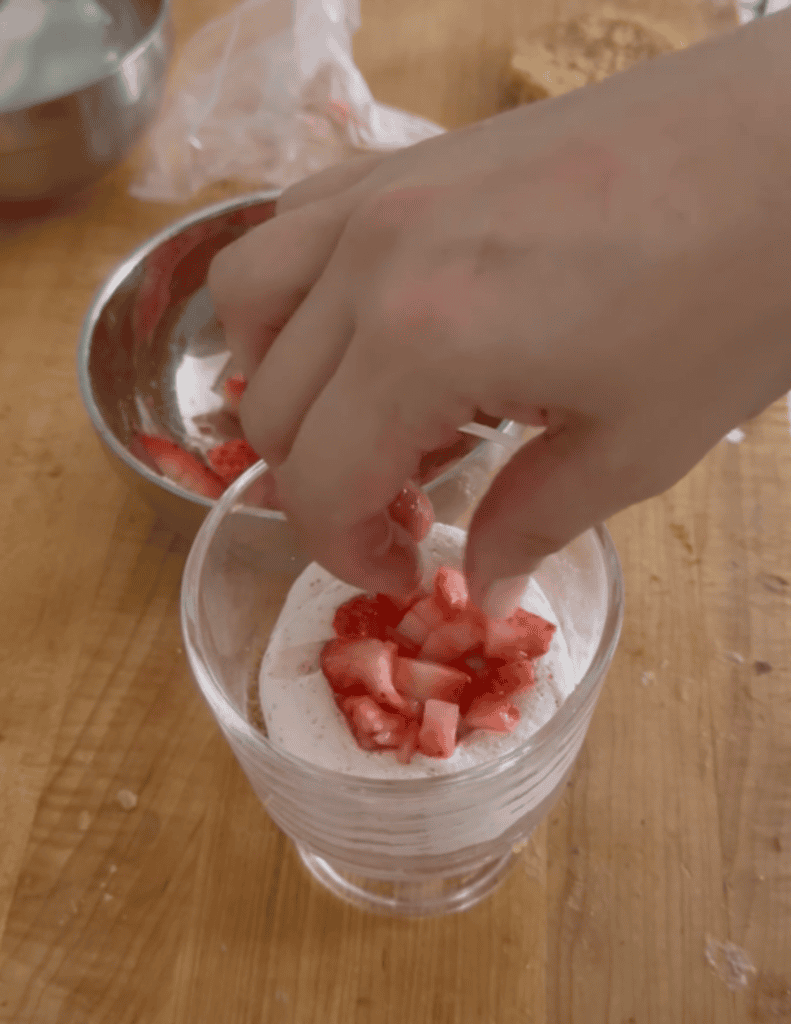 Adding fresh strawberries to gluten-free strawberry trifle dessert.